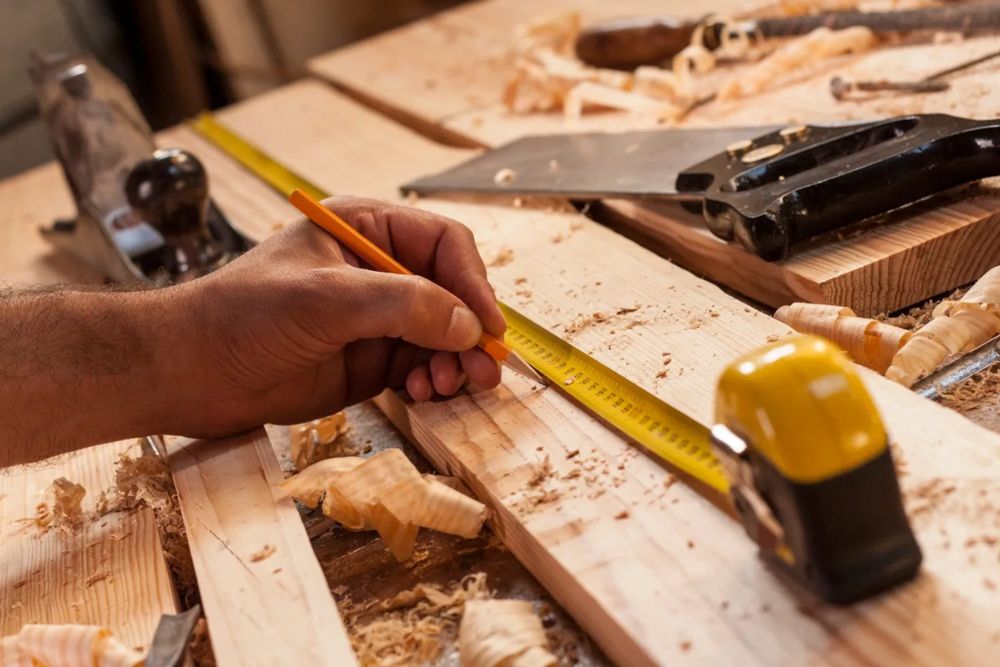 A person measuring a piece of wood with a measuring tape, focusing intently on the measurement.